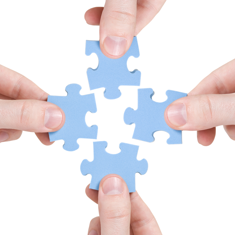teamwork and partnership concept. four hands connecting puzzle