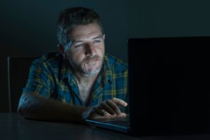 image of a man in front of a laptop with poor lighting