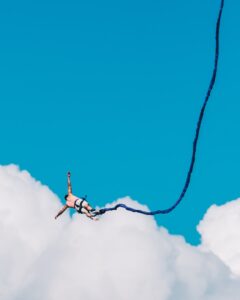 man falling through the sky attached to a bungee cord