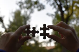 Image of two hands putting two puzzle pieces together